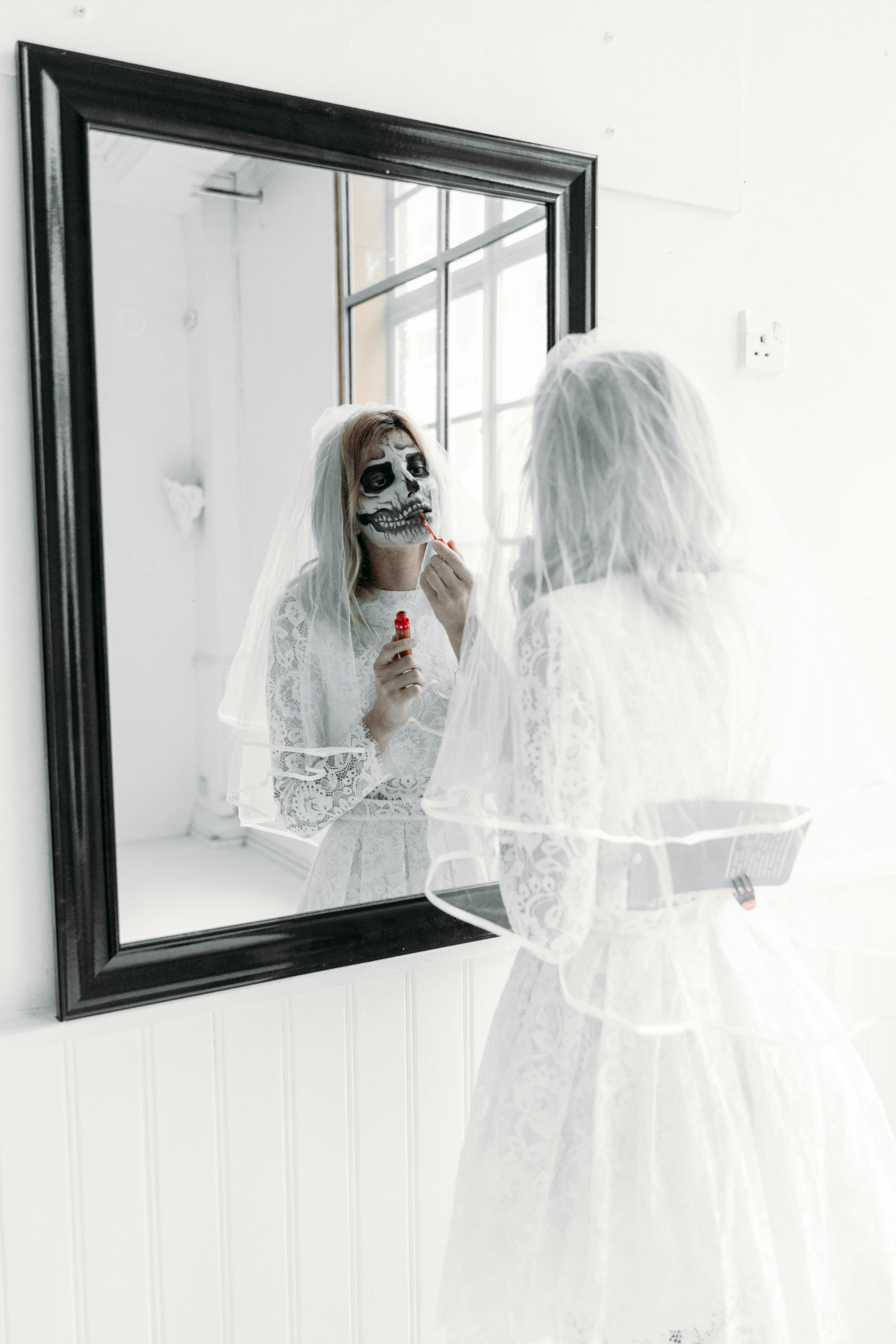 woman with scary face paint applying lipstick