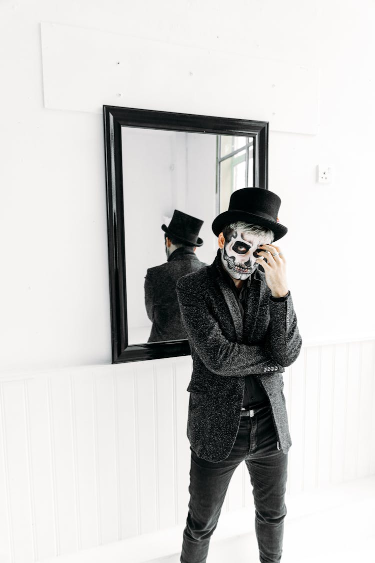 Man In Black Coat And Black Hat Standing Near A Mirror