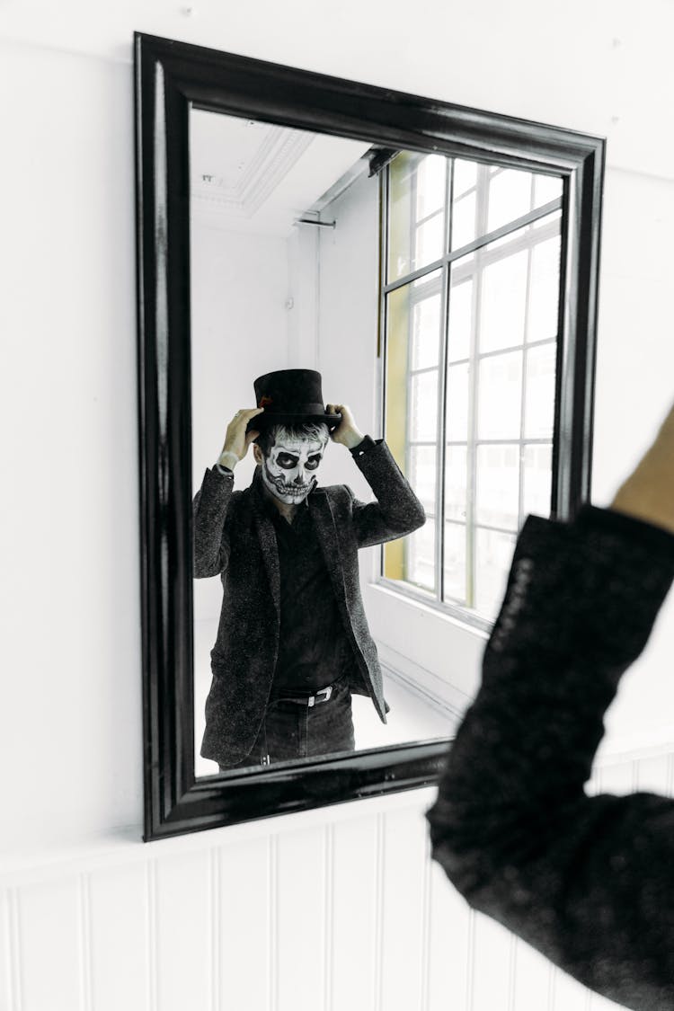 Man Looking In The Mirror While Fixing His Hat