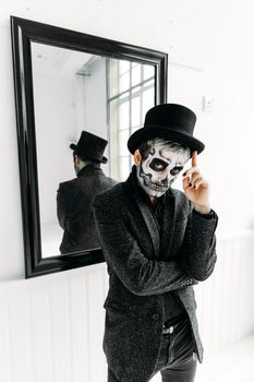 一个戴着高顶礼帽、画着骷髅妆的男人站在镜子前，散发出神秘的氛围