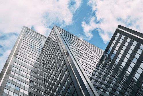 Free From below of contemporary high rise building with glass mirrored windows against cloudy blue sky in daytime Stock Photo