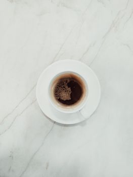 A minimalist flat lay of a coffee cup on a marble surface, ideal for coffee and lifestyle themed content.