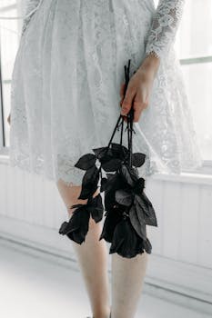 An elegant bride in a lace dress holds black roses, creating a gothic wedding theme.