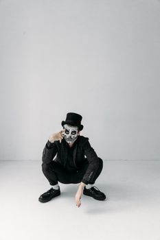 在简约的工作室背景映衬下，一个头戴礼帽、画着骷髅妆的男人肖像格外醒目