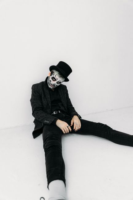Portrait of a man with skull makeup in a stylish outfit and top hat, perfect for Halloween themes.