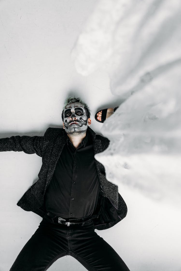 Man In Black With Scary Face Paint Lying On Floor