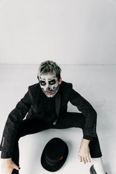 一个脸上涂着骷髅图案的男人在室内摆拍万圣节照片