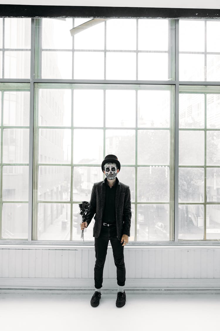 Man With Scary Face Paint Holding A Bunch Of Black Roses