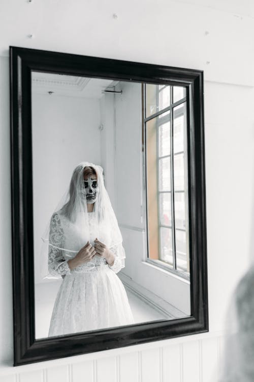 Reflet D'une Femme En Robe De Mariée Blanche Avec De La Peinture Pour Le Visage Effrayant