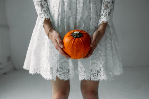 Donna In Vestito Dalla Manica Lunga Del Pizzo Bianco Che Tiene La Zucca