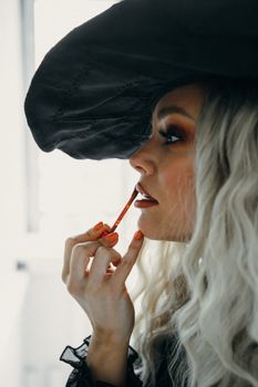 这是一张非常适合万圣节主题的特写肖像，画面中的女人戴着巫婆帽子，涂着口红
