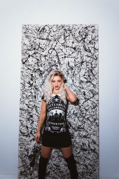 一位金发碧眼的女人身着时髦的哥特式服装，在抽象背景前摆出姿势