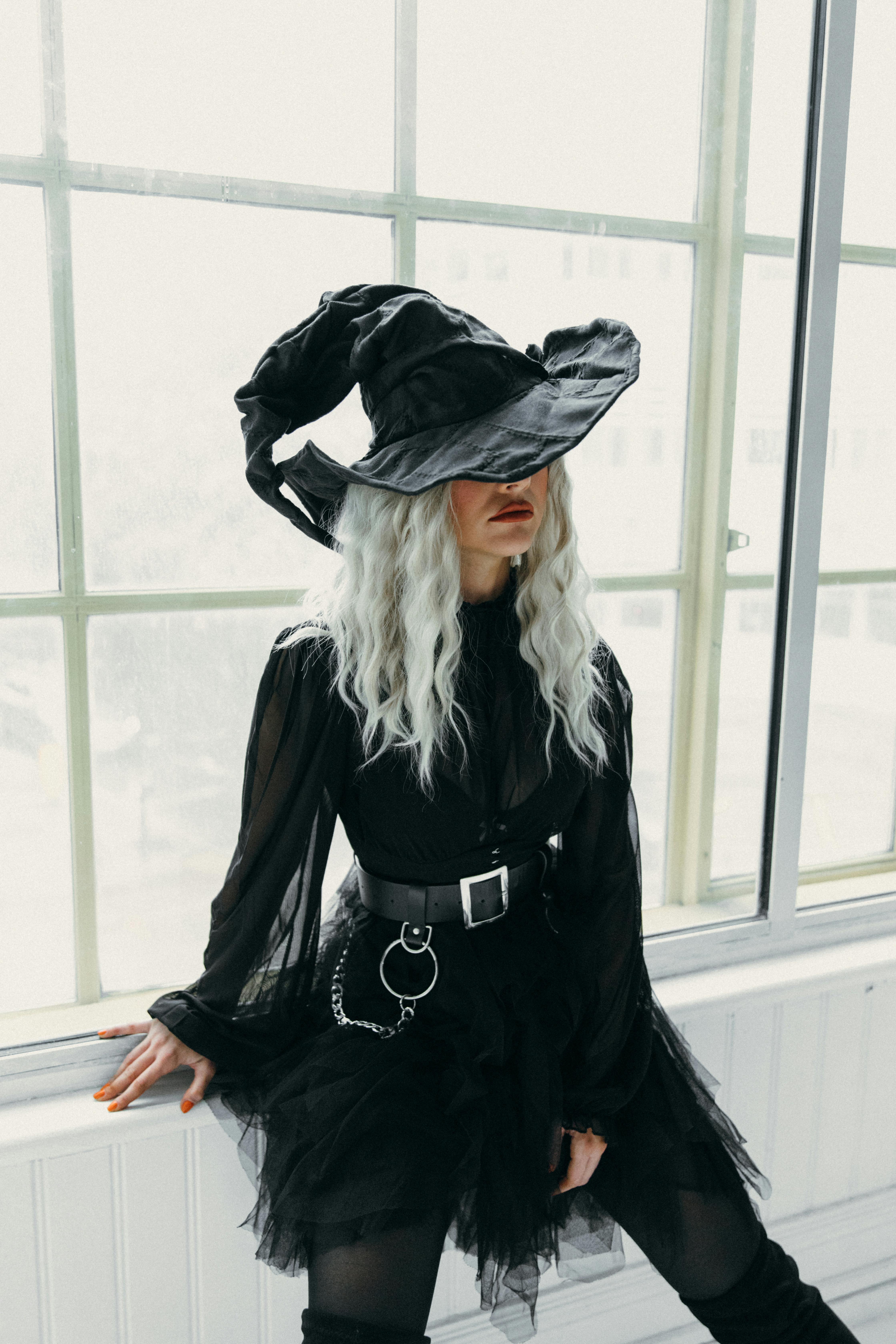 一个女人身穿女巫服装，坐在窗户旁，营造出一种神秘的氛围