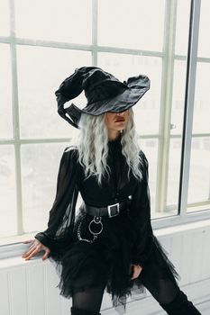 一个女人身穿女巫服装，坐在窗户旁，营造出一种神秘的氛围