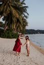 两名女子手牵着手，沿着热带海滩散步，享受着宁静的假期时光