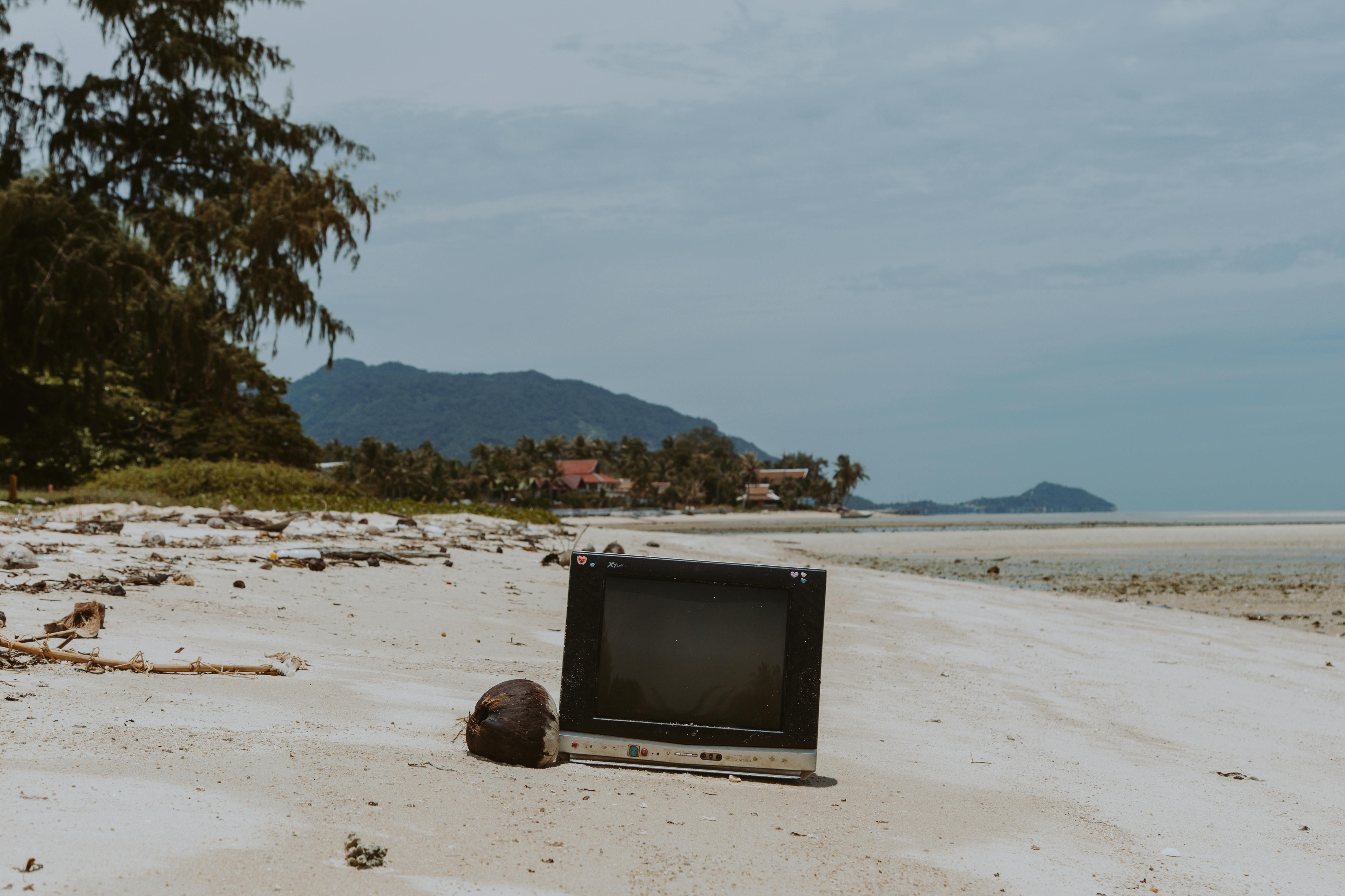 An old tv in the sand of a beautiful beach