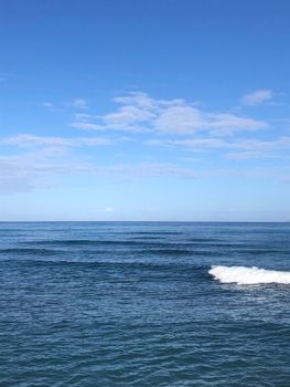 Peaceful ocean scene with gentle waves and a vast blue sky, perfect for relaxation themes.