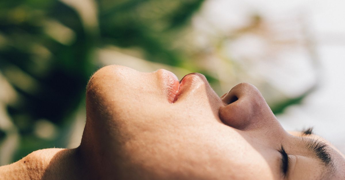 Close-up side view of a relaxed man with eyes closed outdoors.