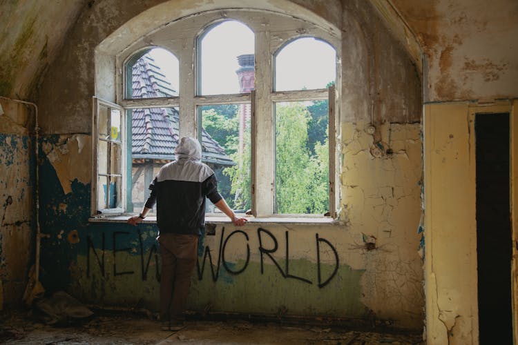 Anonymous Man Standing Near Window In Destroyed House