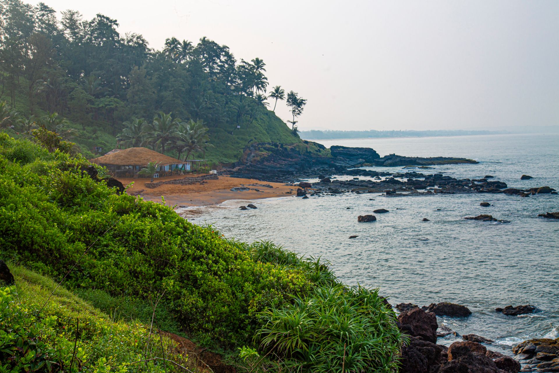 Explore the lush green coastline of Goa with its vibrant beach and rocky shores.