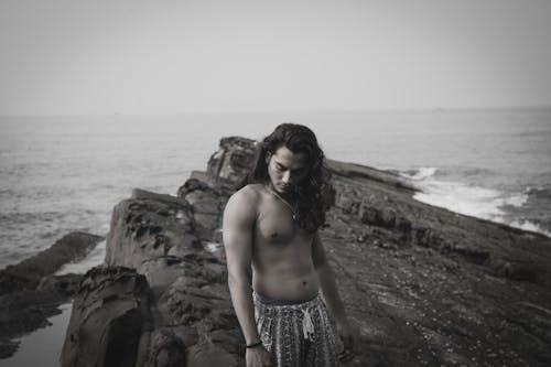 Free Photograph of a Shirtless Man with Long Hair Standing Near the Sea Stock Photo