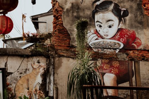 这幅充满活力的壁画描绘了一个孩子与一只猫吃面条的情景，展现了街头艺术的魅力