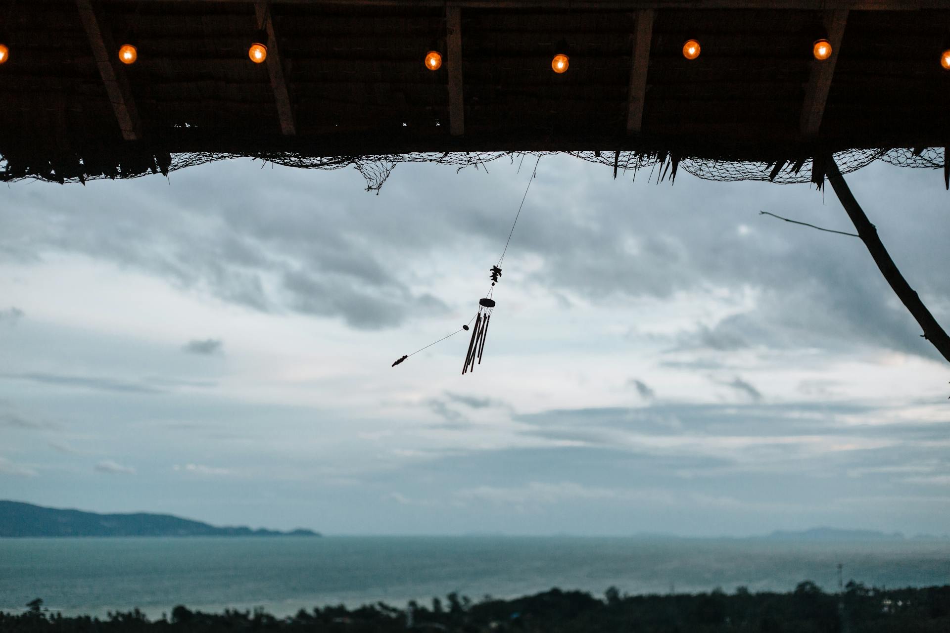 A peaceful ocean view with a wind chime hanging under a canopy, perfect for relaxation and meditation visuals.