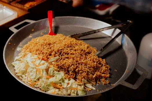 Close-up of stir-fried noodles with cabbage cooked in a large wok.