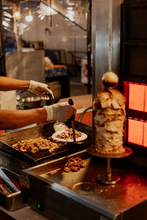 Free Chef prepares doner kebab with fresh ingredients at a food stall. Stock Photo
