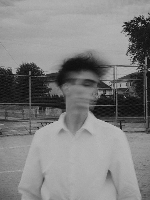 Black and white image of a young man with blurred motion in an urban environment.