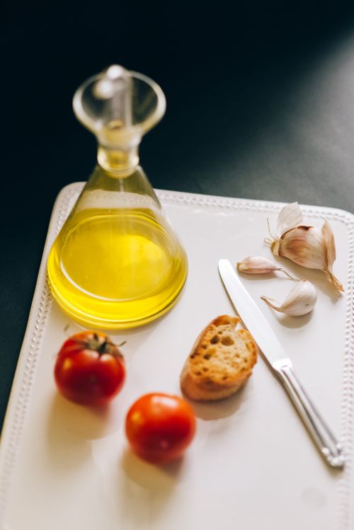 Free Fresh tomatoes, garlic, and olive oil on a white tray, perfect for bruschetta preparation. Stock Photo