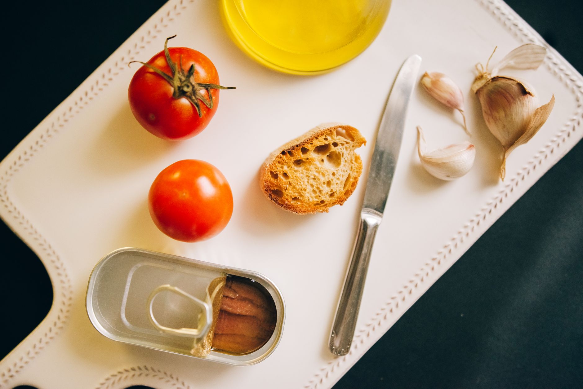 Assorted cans of tuna, salmon, and sardines arranged on a wooden table with fresh herbs and lemons