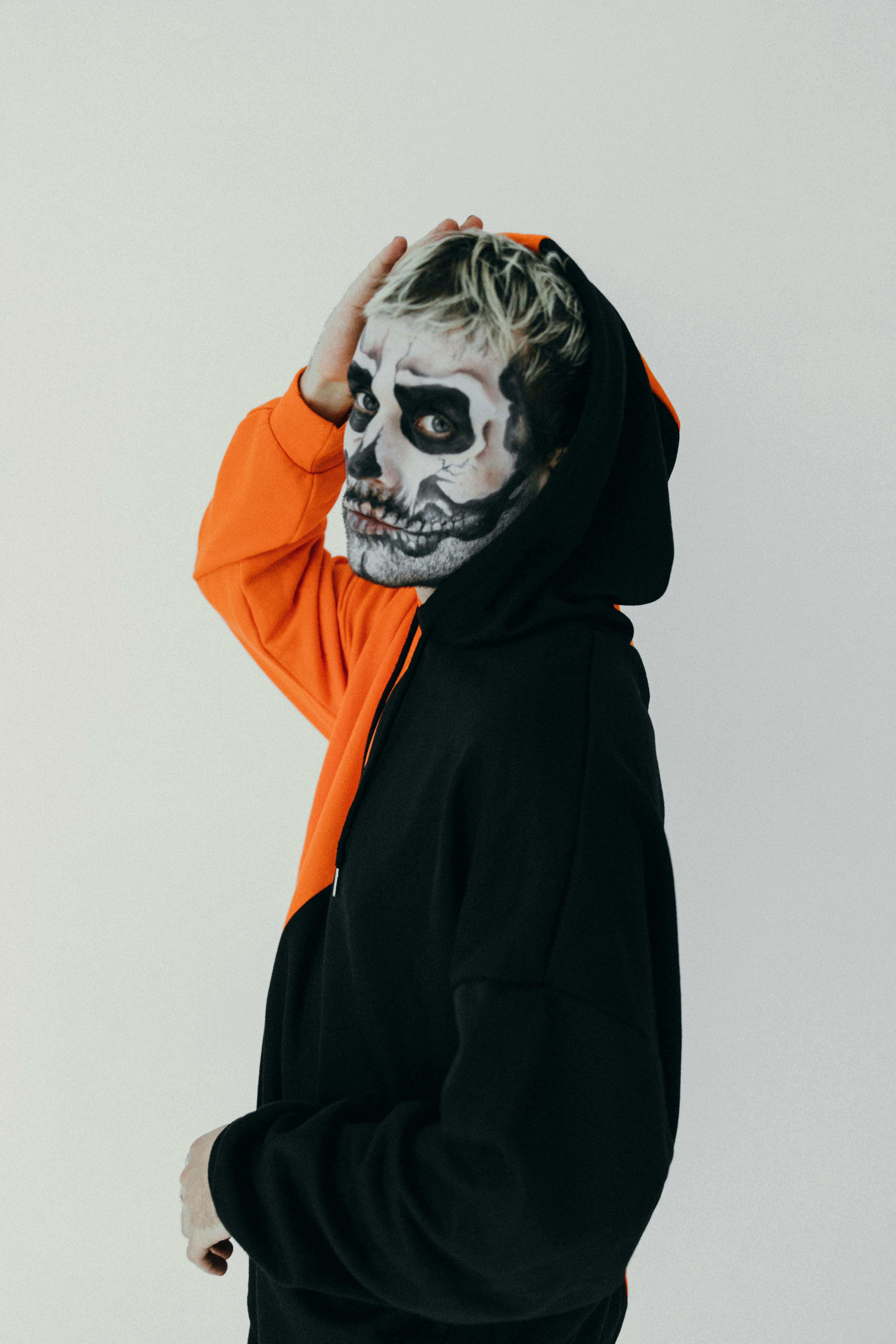 person in black and orange hoodie with halloween face art