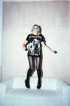 Woman in skull face paint jumping on a sofa, capturing a playful Halloween vibe.