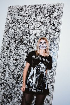 一名女子化着骷髅妆，穿着格林主题服装，站在抽象背景下