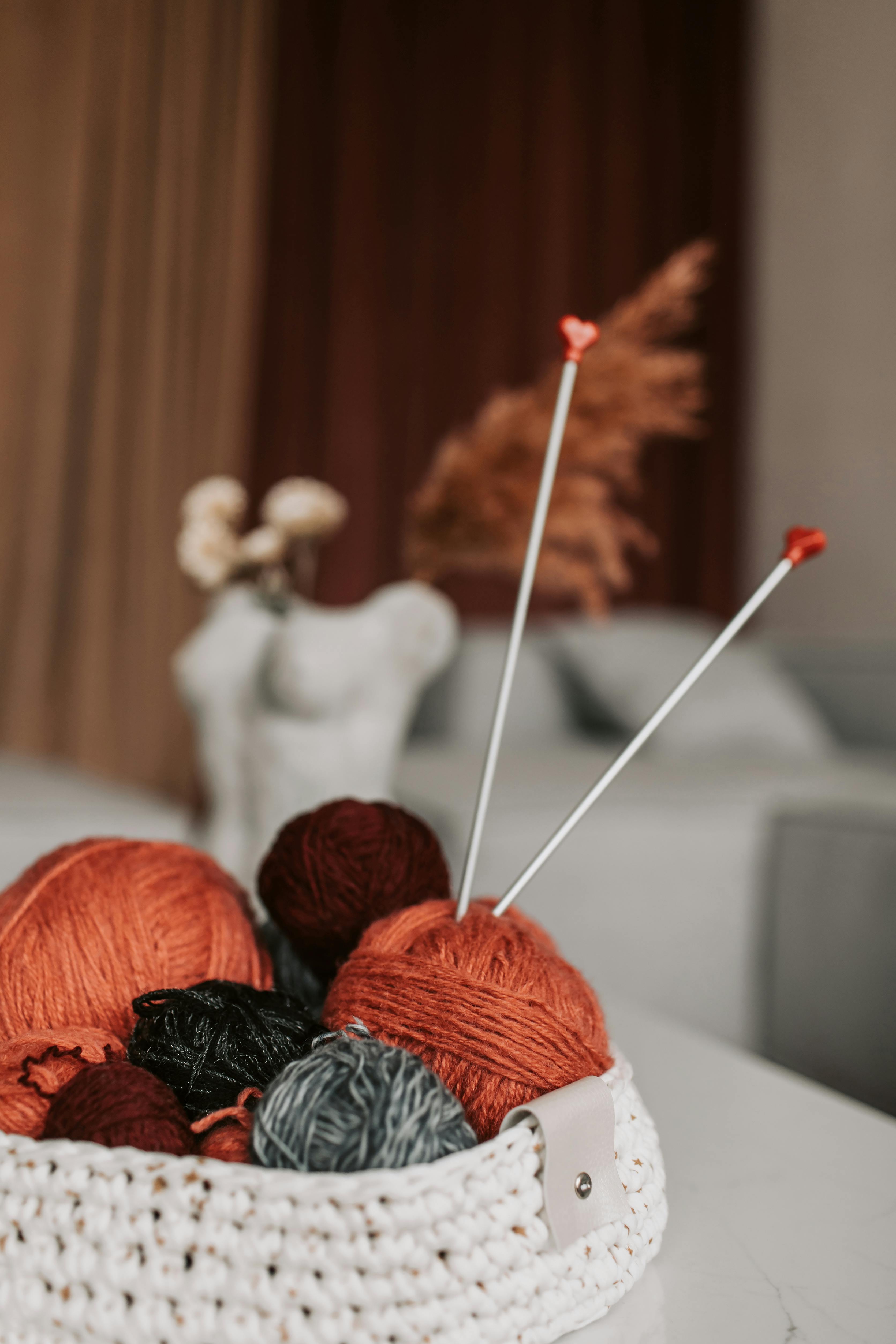 A cozy indoor setting with a basket of colorful yarns and knitting needles, perfect for crafting enthusiasts.