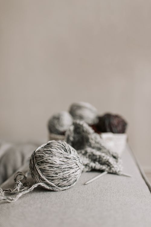 Free Close-up of knitting yarn balls and needles on a neutral background, perfect for craft projects. Stock Photo