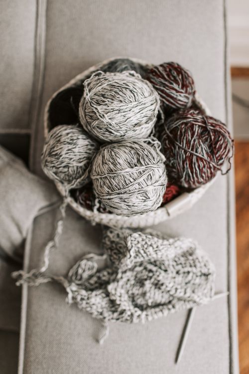 Free Basket filled with yarn balls, needles, and knitted fabric on a cozy armchair. Stock Photo