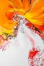 Abstract background painting with red splatters on white fluid acrylic paint and orange stains creating original patterns on creative drawing