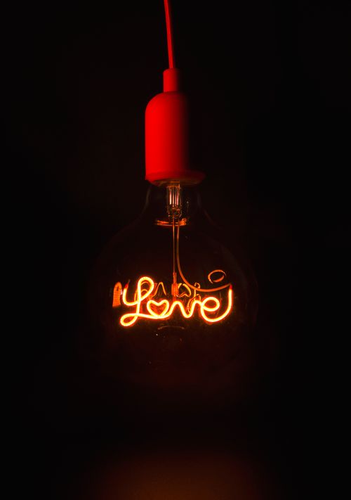 Free Close-up of a glowing LED bulb with 'love' filament on a dark background. Stock Photo