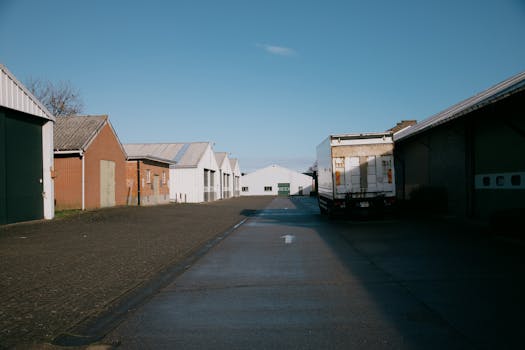 A sunny day at a rural warehouse with a parked truck on an empty road.