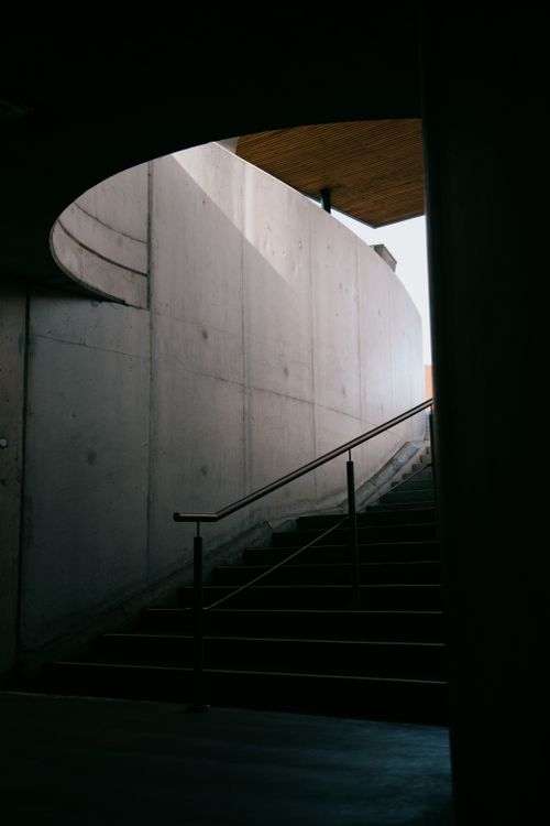 Free Long thin railing and staircase by tall grey wall to underground passage in daytime Stock Photo
