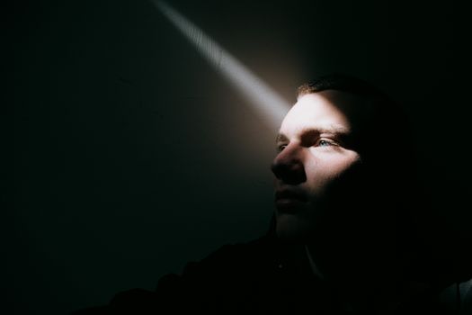 一道光线部分照亮了一个男人的脸，唤起沉思和神秘