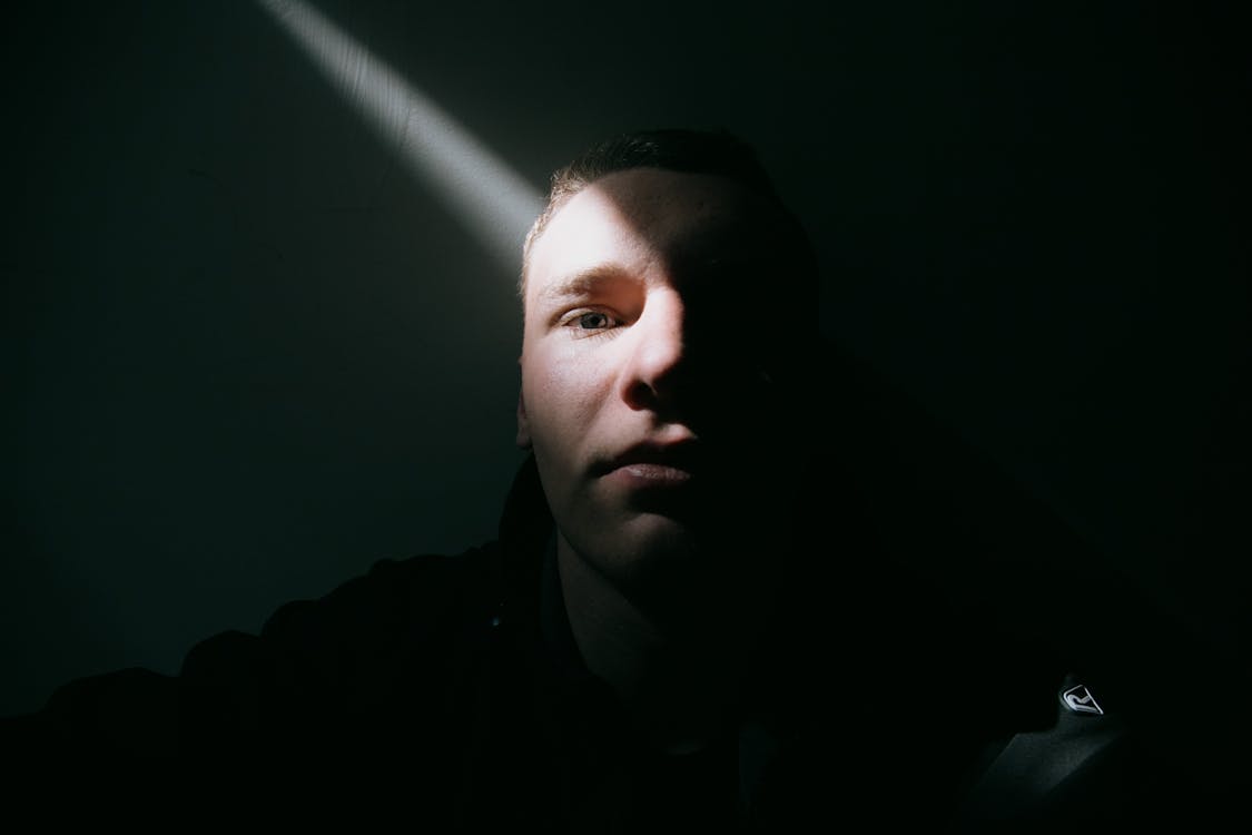 manifest using visualization - Free Pensive young male with short hair thoughtfully looking at camera by wall in dark room in sunlight Stock Photo