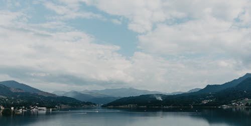 Body of Water Near Mountain Under Cloudy Sky