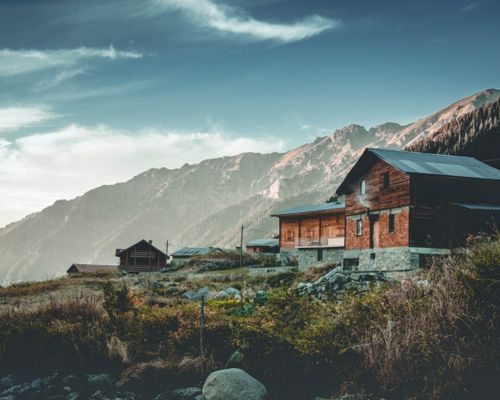 Free Charming wooden chalet set against breathtaking mountain backdrop, ideal for nature and travel enthusiasts. Stock Photo