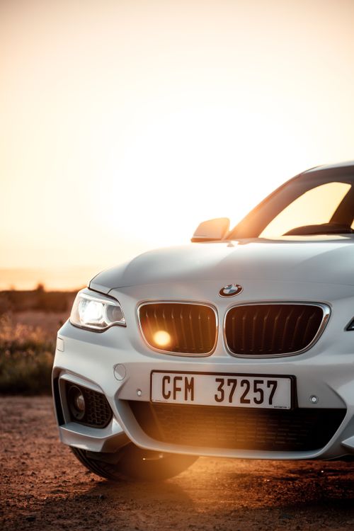 Free Captivating shot of a white BMW coupe at sunset on a scenic road in Cape Town, South Africa. Stock Photo