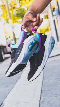 Close-up of colorful Nike sneakers being held outdoors, capturing urban fashion essence.