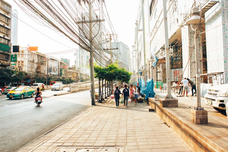A bustling city street with pedestrians, vehicles, and ongoing construction work.