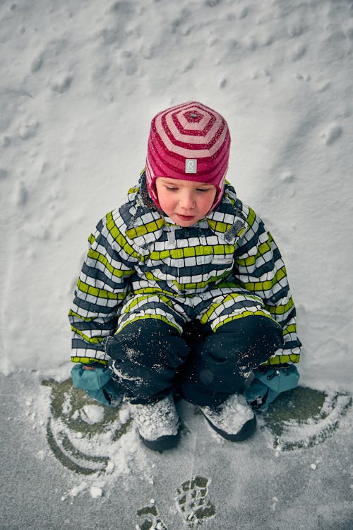 Free A Child Sitting on the Ground with Snow Stock Photo